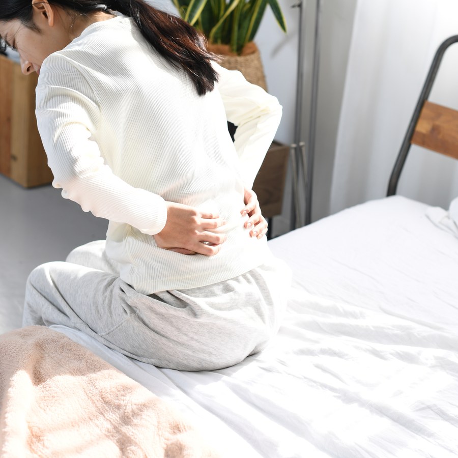 腰の痛みに手を当てる女性